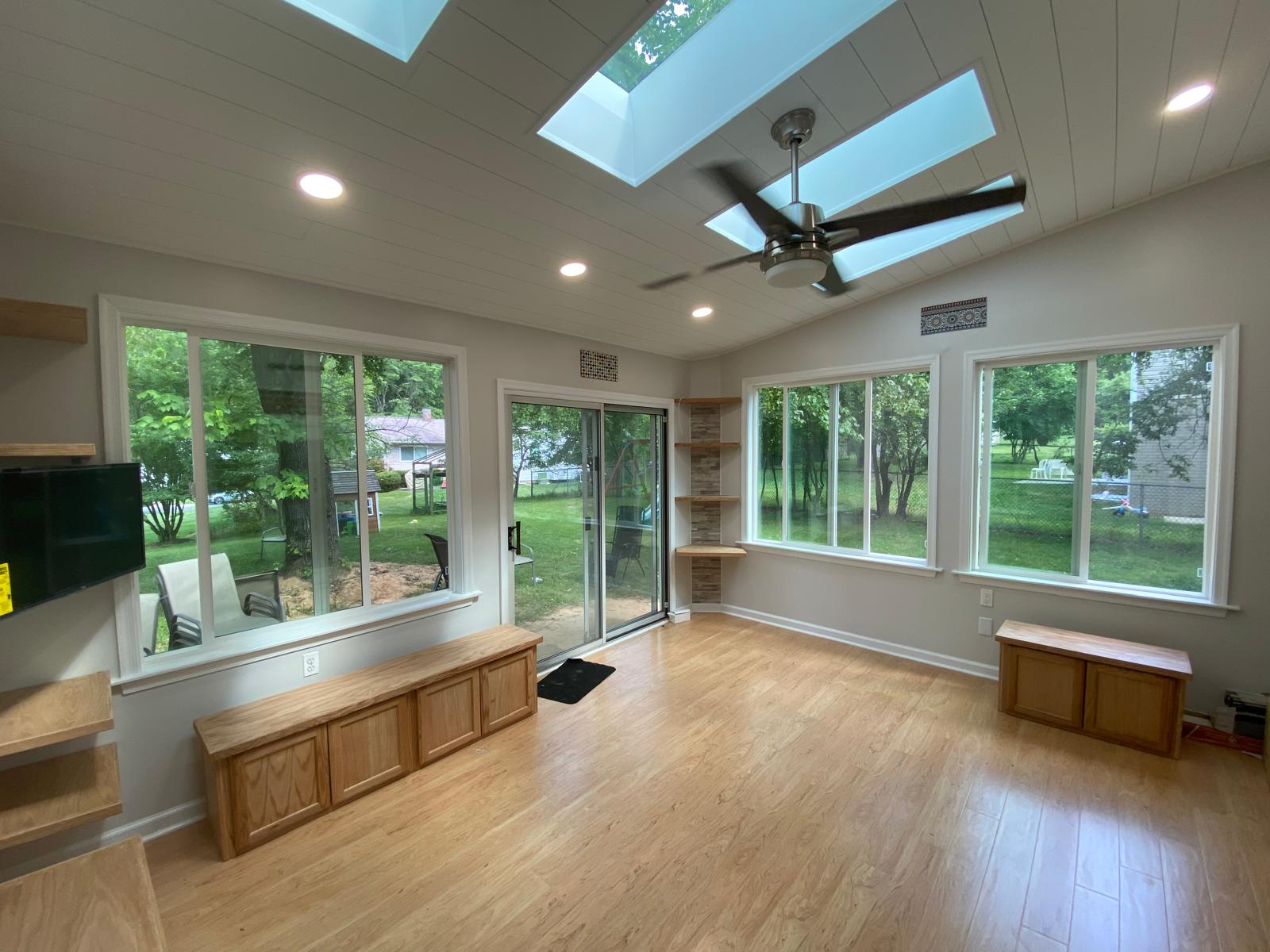 After — finished sunroom with shiplap ceiling, skylights, recessed lighting and hardwood floors