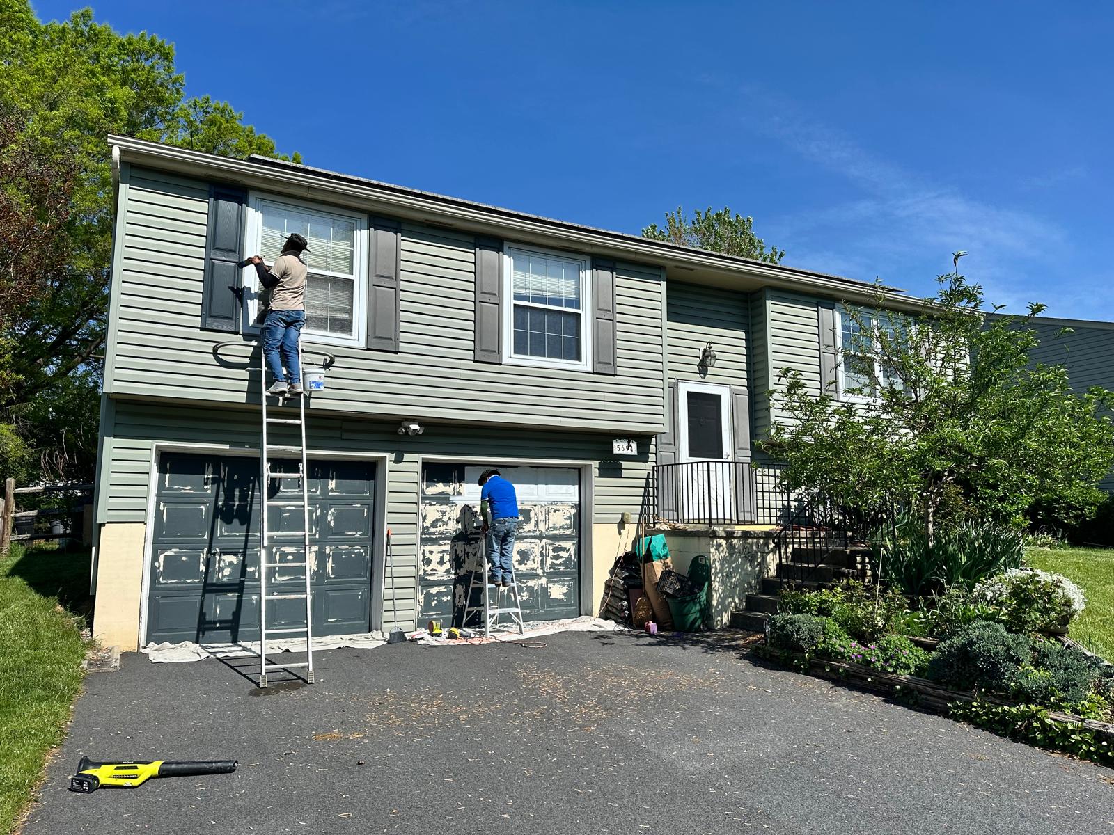 Before — crew prepping siding and worn garage doors for painting