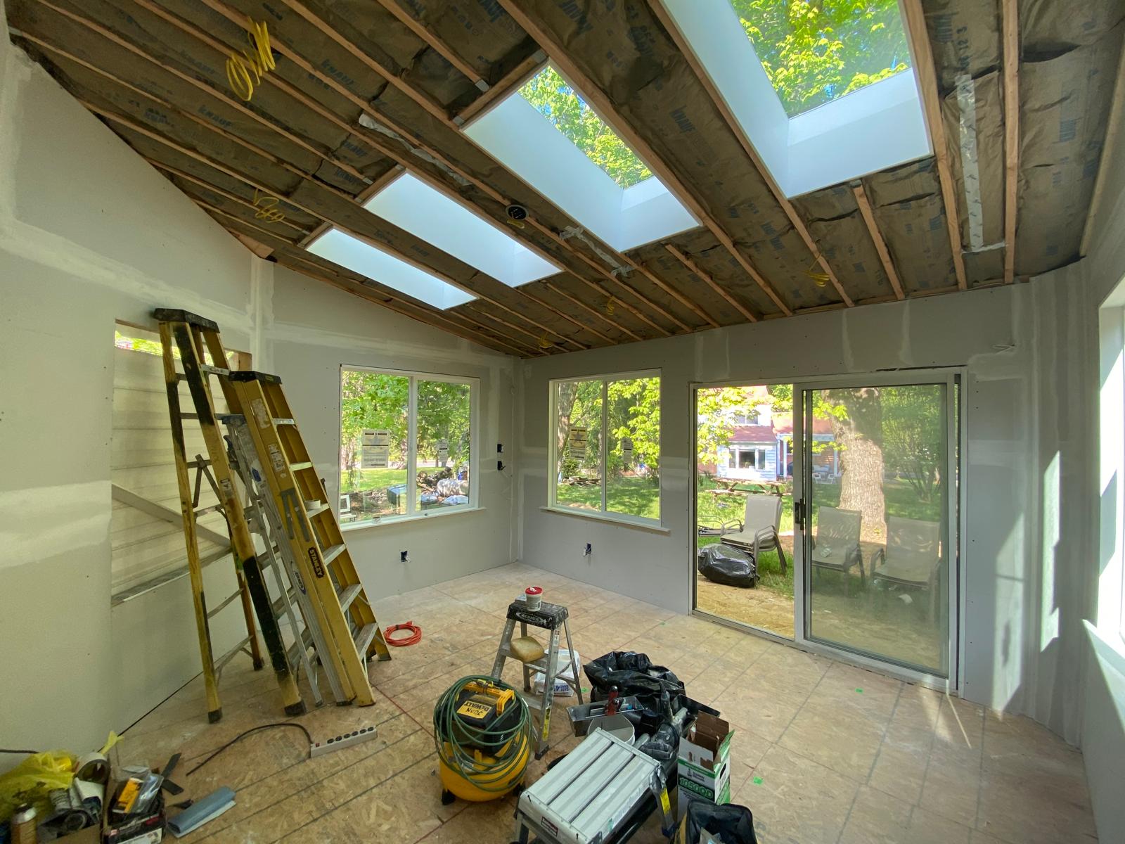 Before — sunroom under construction with open ceiling framing, skylights and tools